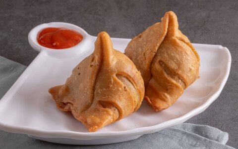 Two crispy vegetable samosas with tomato chutney at Tandoori Smoke Indian restaurant Bangkok