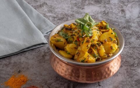 Jeera aloo, potatoes with cumin and coriander in a copper bowl at Tandoori Smoke Indian restaurant Bangkok